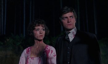 Movie still from “The Devil Rides Out” (1968), directed by Terence Fisher – A man and a woman standing next to each other; Medium shot, Low angle