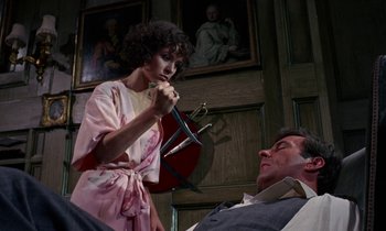 Movie still from “The Devil Rides Out” (1968), directed by Terence Fisher – A woman holding a pair of scissors next to a man's face; Medium shot, Low angle