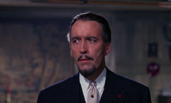Movie still from “The Devil Rides Out” (1968), directed by Terence Fisher – A person wearing a suit and tie; Close Up shot, Over the shoulder angle