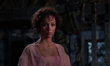 Movie still from “The Devil Rides Out” (1968), directed by Terence Fisher – A woman in a pink dress standing in front of a stone wall; Close Up shot, Low angle