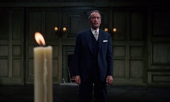 Movie still from “The Devil Rides Out” (1968), directed by Terence Fisher – A man standing in front of a candle in a room; Medium shot, Low angle
