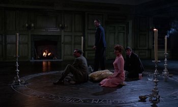 Movie still from “The Devil Rides Out” (1968), directed by Terence Fisher – A group of men and women sitting on the floor; Wide shot, High angle