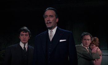 Movie still from “The Devil Rides Out” (1968), directed by Terence Fisher – A group of men standing next to each other in suits; Medium shot, Low angle