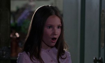 Movie still from “The Devil Rides Out” (1968), directed by Terence Fisher – A girl in a pink shirt is looking surprised; Close Up shot, Over the shoulder angle
