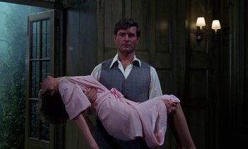 Movie still from “The Devil Rides Out” (1968), directed by Terence Fisher – A man holding a woman in a pink dress; Medium shot, Low angle