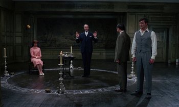 Movie still from “The Devil Rides Out” (1968), directed by Terence Fisher – A group of men and women standing in a circle in front of candles; Wide shot, High angle