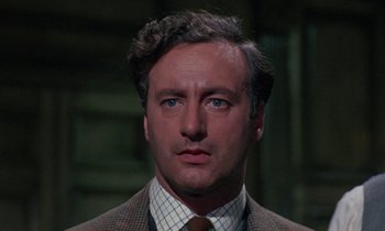 Movie still from “The Devil Rides Out” (1968), directed by Terence Fisher – A person wearing a suit and tie; Close Up shot, Low angle