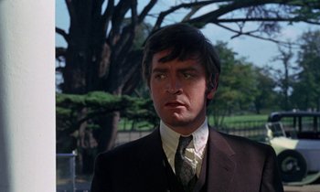 Movie still from “The Devil Rides Out” (1968), directed by Terence Fisher – A man wearing a suit and tie in front of a tree; Close Up shot, Low angle