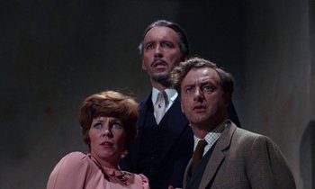 Movie still from “The Devil Rides Out” (1968), directed by Terence Fisher – A group of three people standing next to each other; Medium shot, Low angle