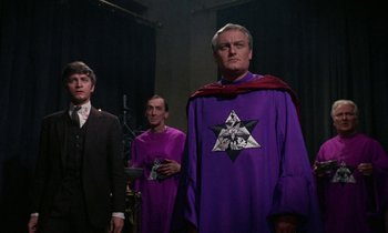 Movie still from “The Devil Rides Out” (1968), directed by Terence Fisher – A group of men standing next to each other; Medium shot, Low angle