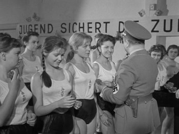 Movie still from “The Devil Strikes at Night” (1957), directed by Robert Siodmak – A group of young women standing next to an officer; Medium shot, Over the shoulder angle