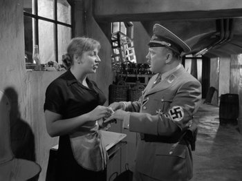 Movie still from “The Devil Strikes at Night” (1957), directed by Robert Siodmak – An old photo of a man and a woman; Medium shot, Over the shoulder angle