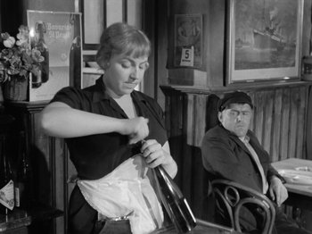 Movie still from “The Devil Strikes at Night” (1957), directed by Robert Siodmak – An old photo of a woman and a man in a restaurant; Medium shot, Over the shoulder angle