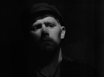 Movie still from “The Devil Strikes at Night” (1957), directed by Robert Siodmak – A man with a beard wearing a hat and a suit; Close Up shot, Low angle