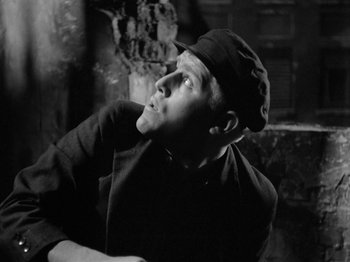 Movie still from “The Devil Strikes at Night” (1957), directed by Robert Siodmak – A black and white photo of a man with a hat; Close Up shot, Low angle