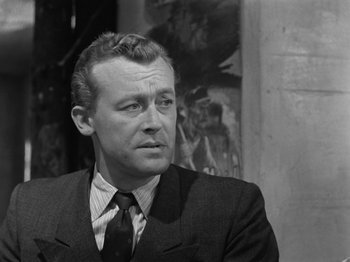 Movie still from “The Devil Strikes at Night” (1957), directed by Robert Siodmak – An old black and white photo of a man in a suit; Close Up shot, Over the shoulder angle