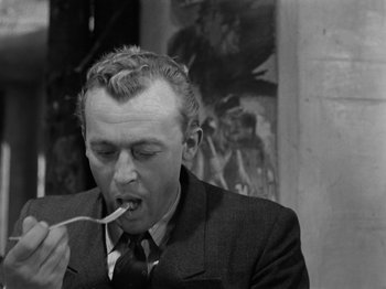 Movie still from “The Devil Strikes at Night” (1957), directed by Robert Siodmak – A black and white photo of a man eating a piece of food; Close Up shot, High angle