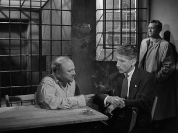 Movie still from “The Devil Strikes at Night” (1957), directed by Robert Siodmak – Two men sitting at a table talking to each other; Medium shot, Over the shoulder angle