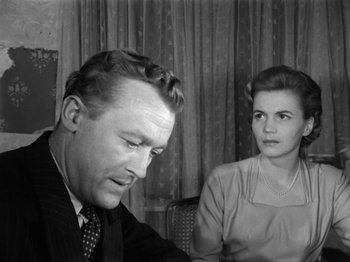 Movie still from “The Devil Strikes at Night” (1957), directed by Robert Siodmak – An old photo of a man and a woman sitting at a table; Close Up shot, Over the shoulder angle
