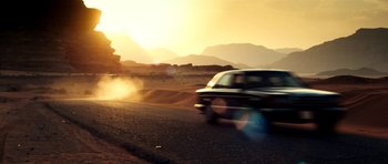 Movie still from “The Devil's Double” (2011), directed by Lee Tamahori – A car driving down a road near a mountain range; Extreme Wide shot, Low angle