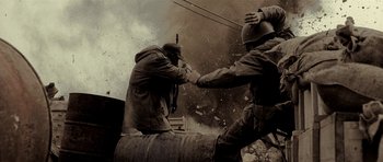 Movie still from “The Devil's Double” (2011), directed by Lee Tamahori – Two men are fighting over a barrel in a war zone; Medium shot, Low angle