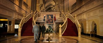 Movie still from “The Devil's Double” (2011), directed by Lee Tamahori – Three men walking up a staircase in front of a painting; Extreme Wide shot, Low angle
