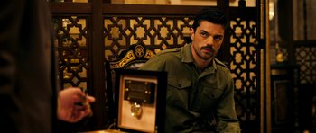 Movie still from “The Devil's Double” (2011), directed by Lee Tamahori – A man sitting in a chair in front of an antique clock; Medium shot, Over the shoulder angle