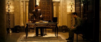 Movie still from “The Devil's Double” (2011), directed by Lee Tamahori – A man standing at a desk in front of a computer; Wide shot, Over the shoulder angle