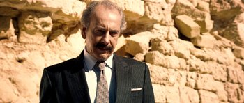 Movie still from “The Devil's Double” (2011), directed by Lee Tamahori – An older man wearing a suit and tie; Close Up shot, Low angle