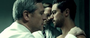 Movie still from “The Devil's Double” (2011), directed by Lee Tamahori – Three men in suits are looking at each other; Close Up shot, Over the shoulder angle