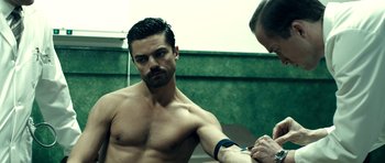 Movie still from “The Devil's Double” (2011), directed by Lee Tamahori – A man is getting his arm examined by a doctor; Medium shot, High angle