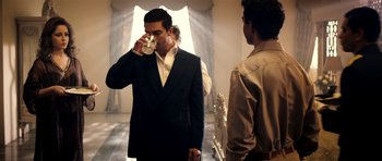Movie still from “The Devil's Double” (2011), directed by Lee Tamahori – A man in a suit drinking a glass of water; Medium shot, Over the shoulder angle