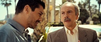 Movie still from “The Devil's Double” (2011), directed by Lee Tamahori – Two men talking to each other in front of palm trees; Close Up shot, Over the shoulder angle