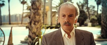 Movie still from “The Devil's Double” (2011), directed by Lee Tamahori – An older man in a suit and tie; Close Up shot, Low angle