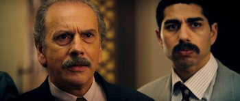 Movie still from “The Devil's Double” (2011), directed by Lee Tamahori – A man in a suit and tie next to another man in a suit and tie; Close Up shot, Over the shoulder angle