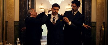 Movie still from “The Devil's Double” (2011), directed by Lee Tamahori – A man in a suit is being fitted for a tie; Medium shot, Low angle