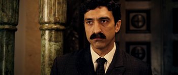 Movie still from “The Devil's Double” (2011), directed by Lee Tamahori – A person wearing a suit and tie; Close Up shot, Over the shoulder angle