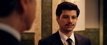 Movie still from “The Devil's Double” (2011), directed by Lee Tamahori – A man in a suit and tie with a mustache; Close Up shot, Over the shoulder angle