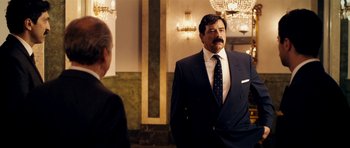 Movie still from “The Devil's Double” (2011), directed by Lee Tamahori – A man wearing a suit and tie standing next to a woman; Medium shot, Over the shoulder angle