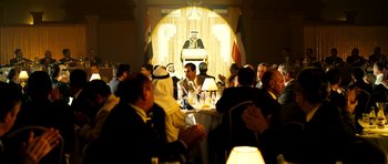 Movie still from “The Devil's Double” (2011), directed by Lee Tamahori – A group of people sitting around a table; Wide shot, Over the shoulder angle