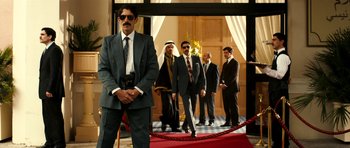 Movie still from “The Devil's Double” (2011), directed by Lee Tamahori – A group of men in suits standing in front of a red carpet; Wide shot, Low angle