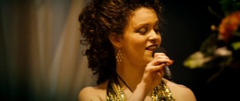 Movie still from “The Devil's Double” (2011), directed by Lee Tamahori – A woman with curly hair is holding a microphone; Close Up shot, Low angle