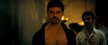 Movie still from “The Devil's Double” (2011), directed by Lee Tamahori – A man with a beard and mustache is posing for a picture; Close Up shot, Over the shoulder angle