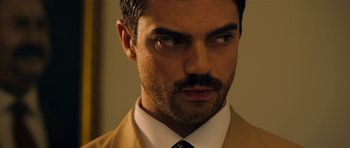 Movie still from “The Devil's Double” (2011), directed by Lee Tamahori – A person wearing a suit and tie; Close Up shot, Over the shoulder angle