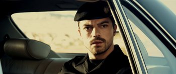 Movie still from “The Devil's Double” (2011), directed by Lee Tamahori – A person in a car wearing a hat; Close Up shot, Over the shoulder angle