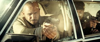 Movie still from “The Devil's Double” (2011), directed by Lee Tamahori – A man holding a gun in a car window; Close Up shot, Low angle