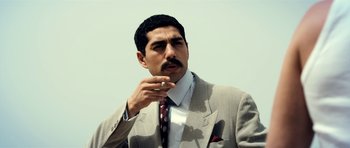 Movie still from “The Devil's Double” (2011), directed by Lee Tamahori – A man in a suit and tie smoking a cigarette; Close Up shot, Low angle