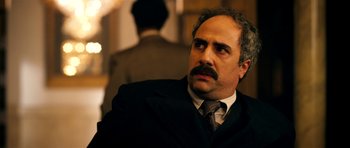 Movie still from “The Devil's Double” (2011), directed by Lee Tamahori – A man in a suit and tie looking up; Close Up shot, Over the shoulder angle