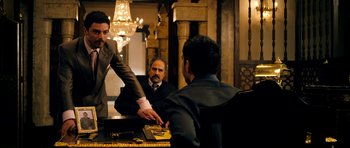 Movie still from “The Devil's Double” (2011), directed by Lee Tamahori – A man in a suit is shaking hands with another man in a suit; Medium shot, Over the shoulder angle