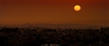 Movie still from “The Devil's Double” (2011), directed by Lee Tamahori – The sun is setting over a large city; Extreme Wide shot, High angle